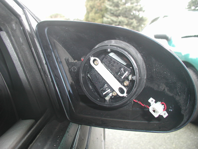 Car side mirror with glass removed showing power actuator and white two-pin wire connector