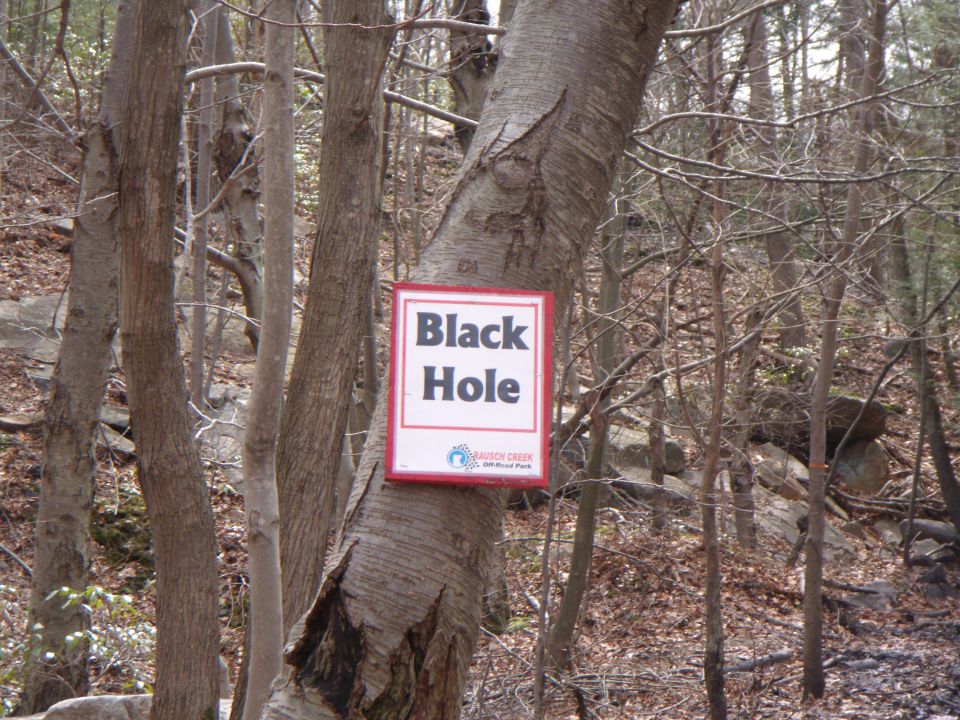 Sign reading "Black Hole" with "Rausch Creek" logo in a wooded area