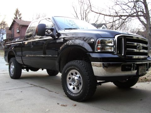 2005 Ford F-250 - A black 2005 Ford F-250 Super Duty pickup truck is parked on a driveway, viewed from the front three-quarter angle.
