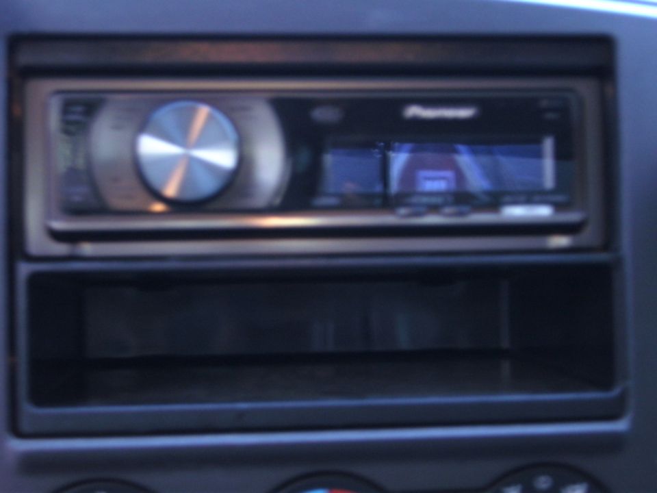 Pioneer car stereo installed in a dashboard slot, with an empty storage compartment below
