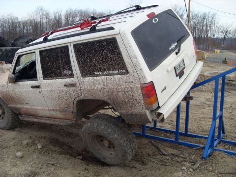 1987 Ford Bronco - This white Jeep Cherokee is covered in mud as it navigates an off-road obstacle course.