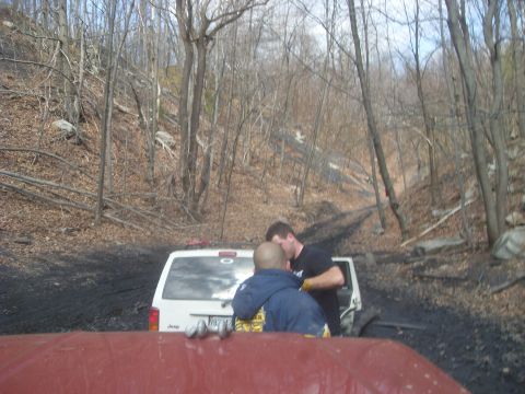 1987 Ford Bronco - Two men stand behind a white Jeep Cherokee on a dirt road in a wooded area.