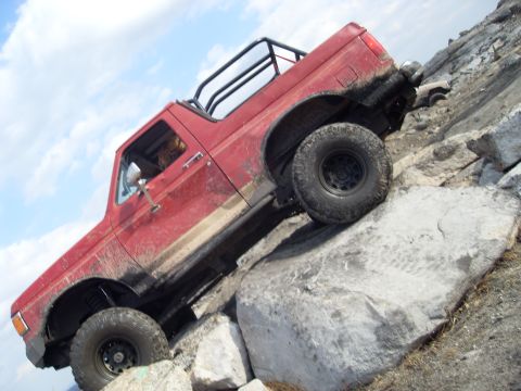 1987 Ford Bronco - A red 1987 Ford Bronco navigates a rocky incline, with another vehicle visible further up the trail.