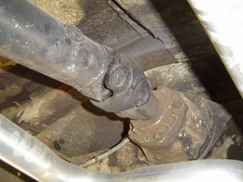 1978 Ford Bronco - Underside view of a vehicle's driveshaft and transfer case assembly.