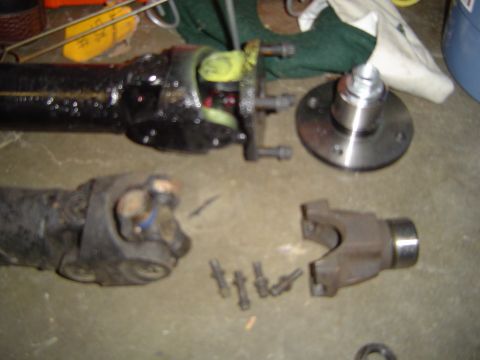 1978 Ford Bronco - Disassembled driveshaft components including U-joints and a flange are laid out on a concrete surface.