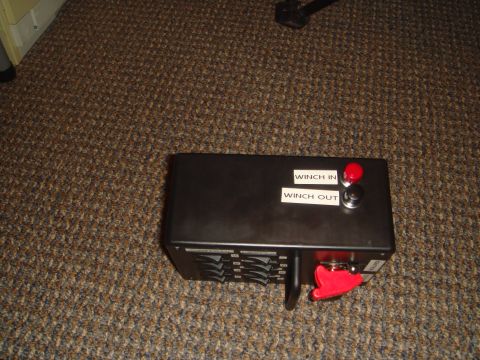 1992 Ford Bronco - A black winch control box with red and black buttons labeled "WINCH IN" and "WINCH OUT" sits on a brown carpeted floor. A red toggle switch…