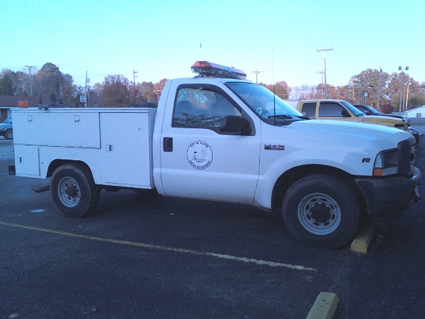 White Ford F-250 utility truck with service body and light bar.