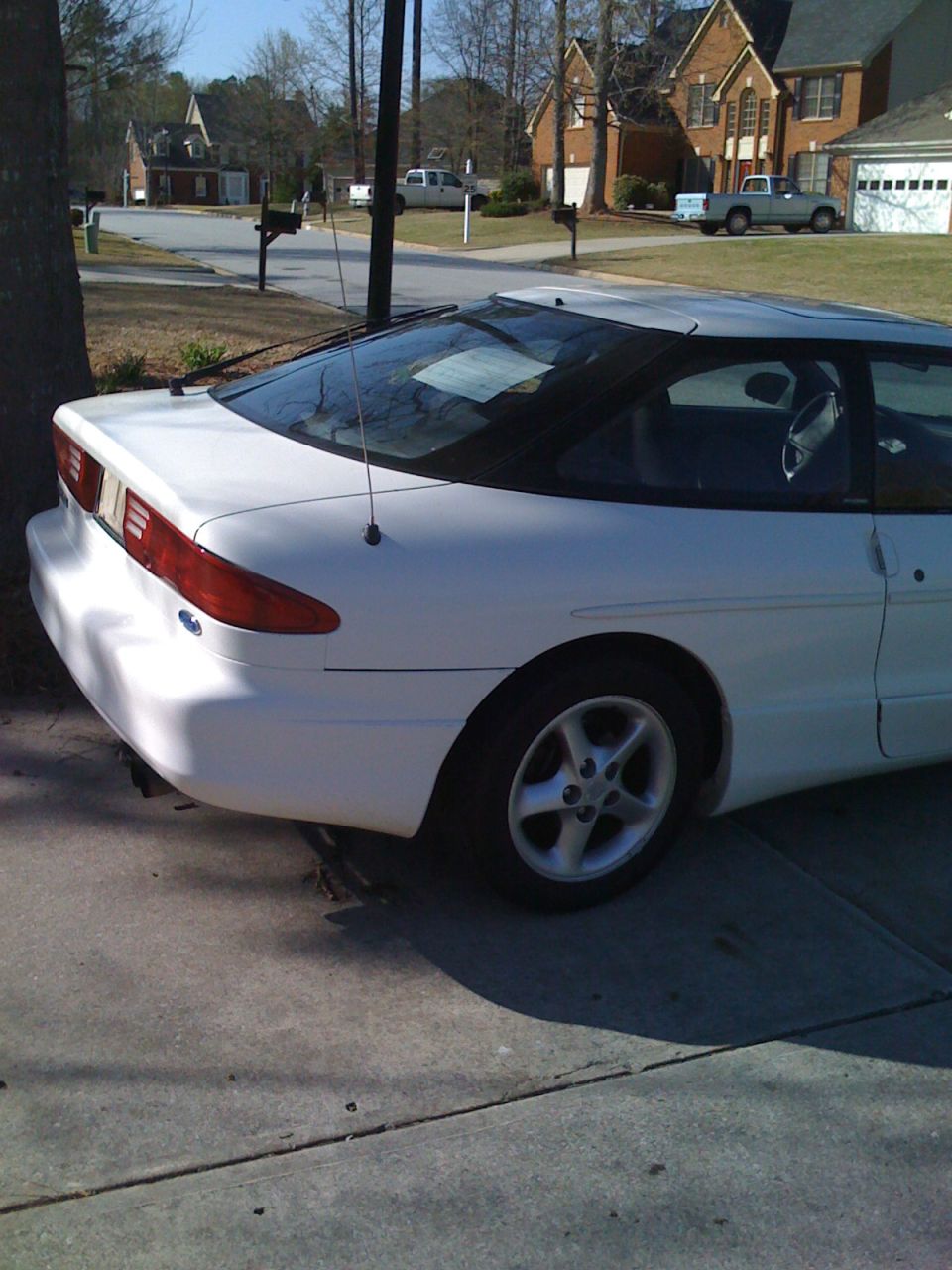 Rear three-quarter view of a white Ford Probe coupe in a driveway