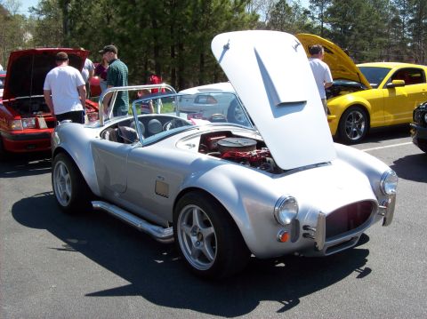 2007 Ford Mustang - A silver convertible sports car with its hood open is parked on asphalt, with a red car and a yellow car visible in the background. Several…