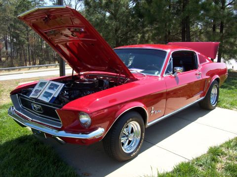 2007 Ford Mustang - A bright red 1967 Ford Mustang fastback is parked on a concrete driveway with its hood and trunk open. Two framed photos of cars are displa…