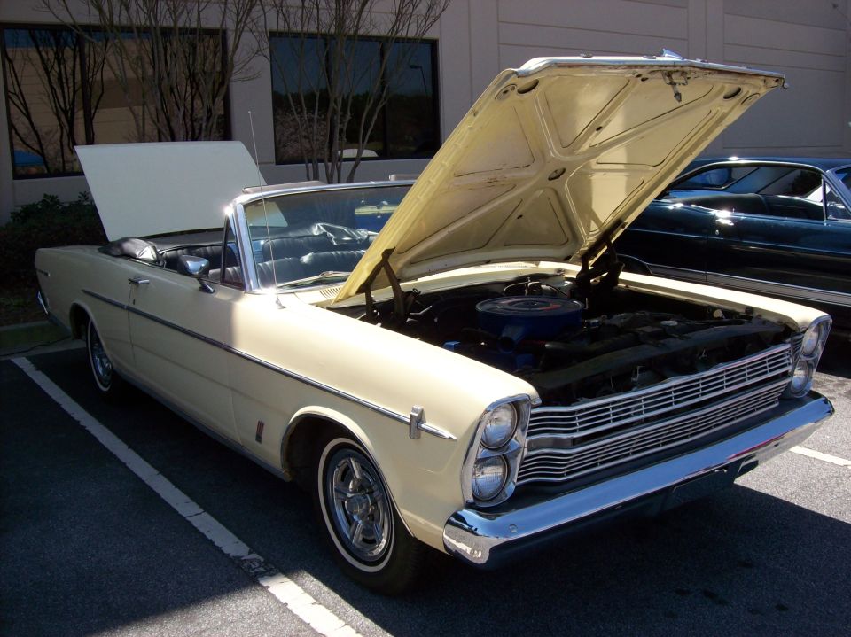 Cream-colored classic convertible with hood open, showing engine.