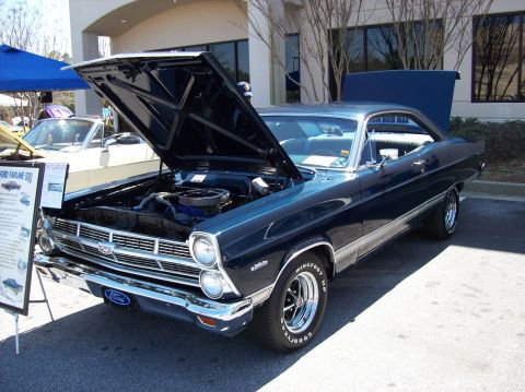 2007 Ford Mustang - A dark blue 1967 Ford Fairlane 500 convertible is displayed with its hood open, showcasing the engine. The car is parked outdoors in front…