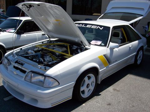 2007 Ford Mustang - A white Saleen Mustang with its hood and trunk open is parked outdoors. The engine bay is visible, showcasing a yellow roll cage and variou…