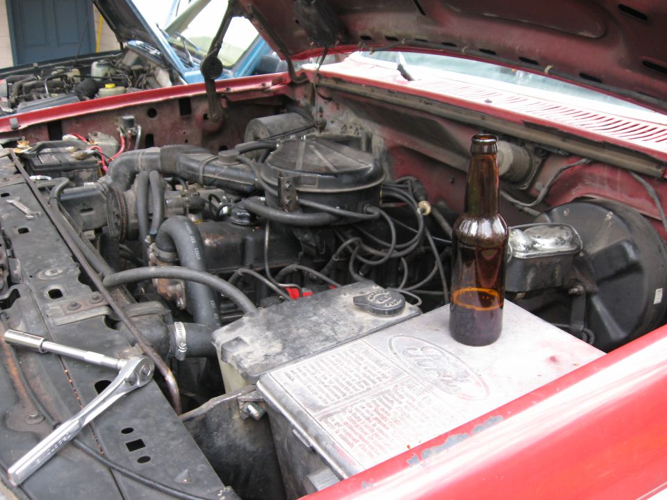 Another shot of the stock engine bay with a view of the engine working necessities.  My brother makes his own beer and brought some over for the job.