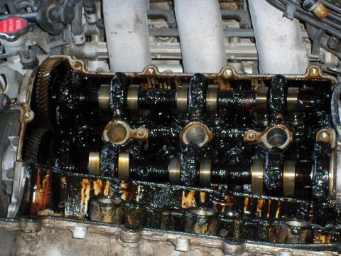 1995 Ford Probe - The interior of an engine's valve cover is heavily coated in black sludge and oil residue.
