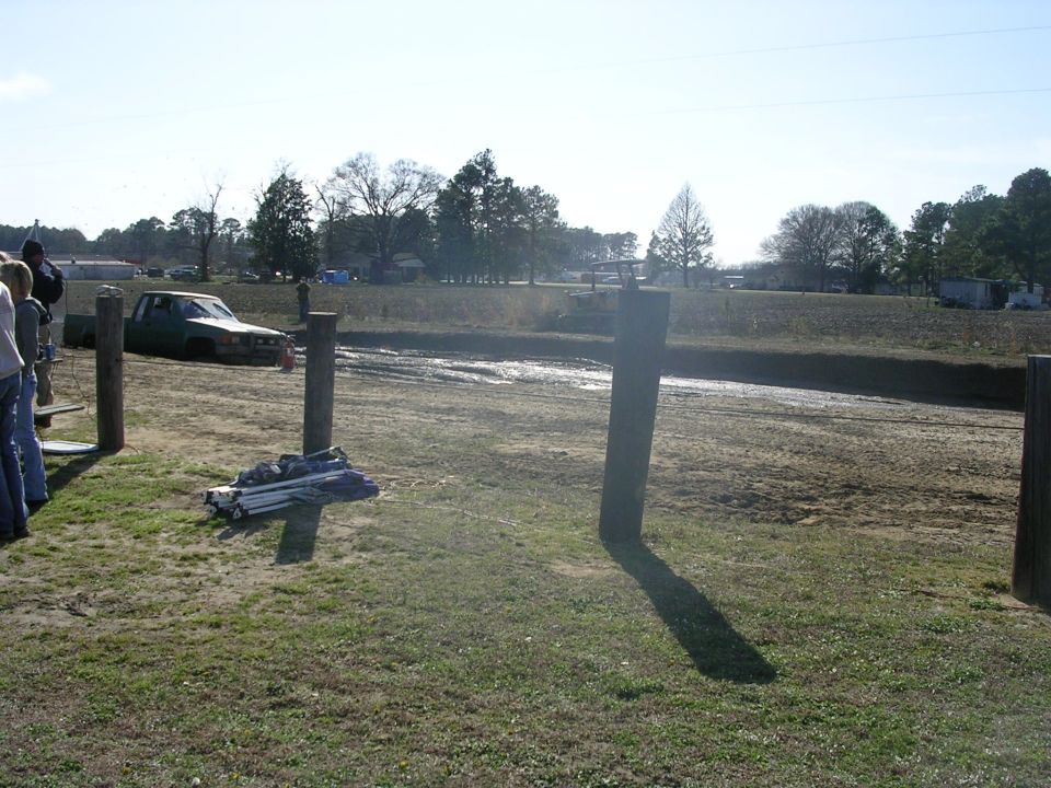 Green pickup truck stuck in mud, front 3/4 view