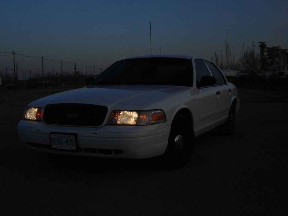 White 2005 Ford Crown Victoria sedan parked at dusk, front view.