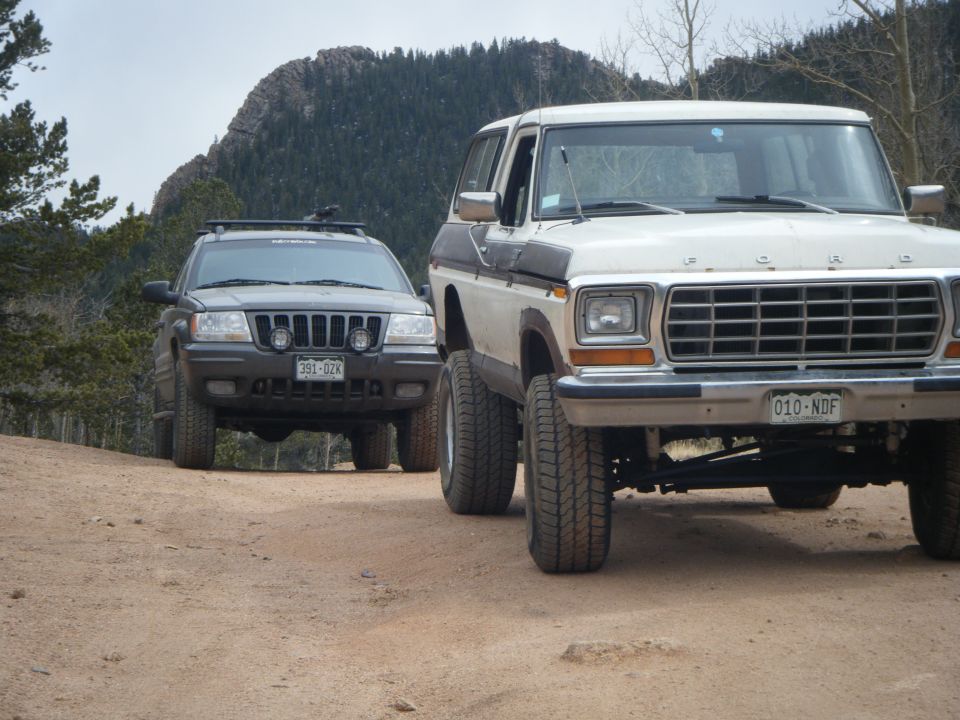 White 1979 Ford Bronco parked on a dirt road with a dark SUV.