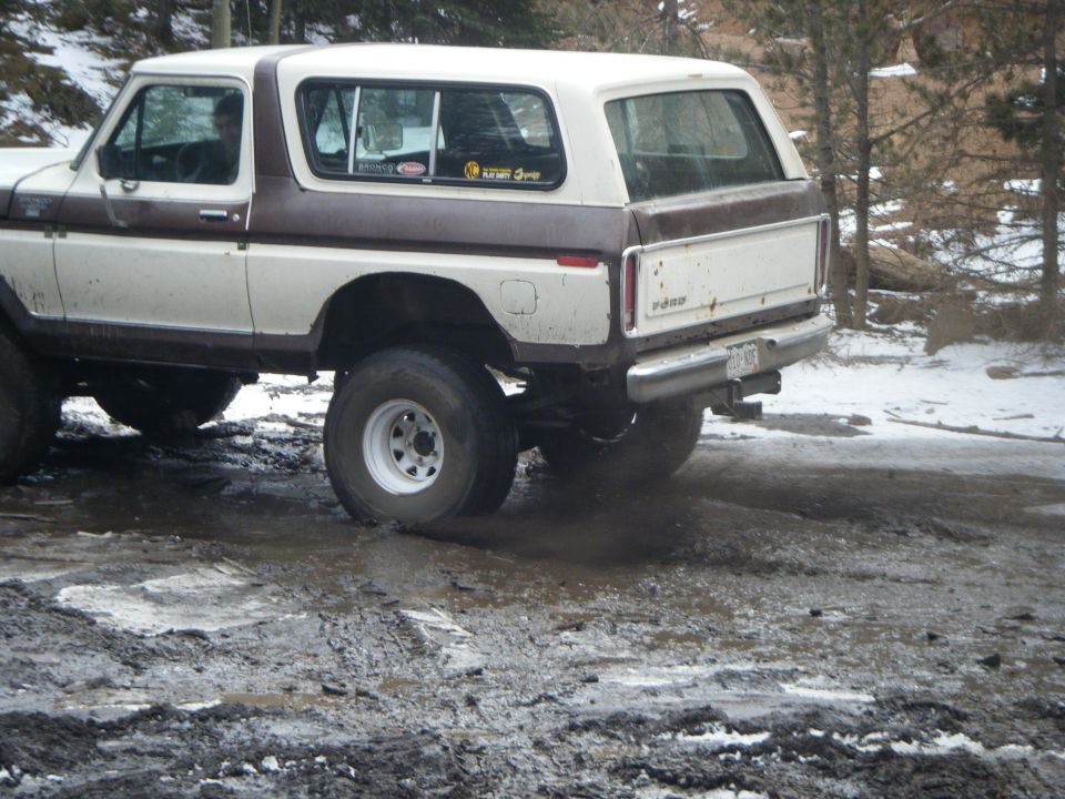 1979 Ford Bronco driving through mud and snow.