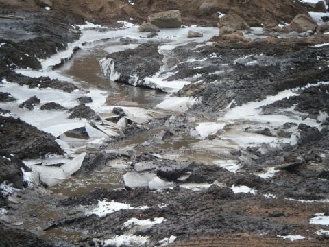1979 Ford Bronco - A muddy and icy landscape with broken ice chunks scattered around.