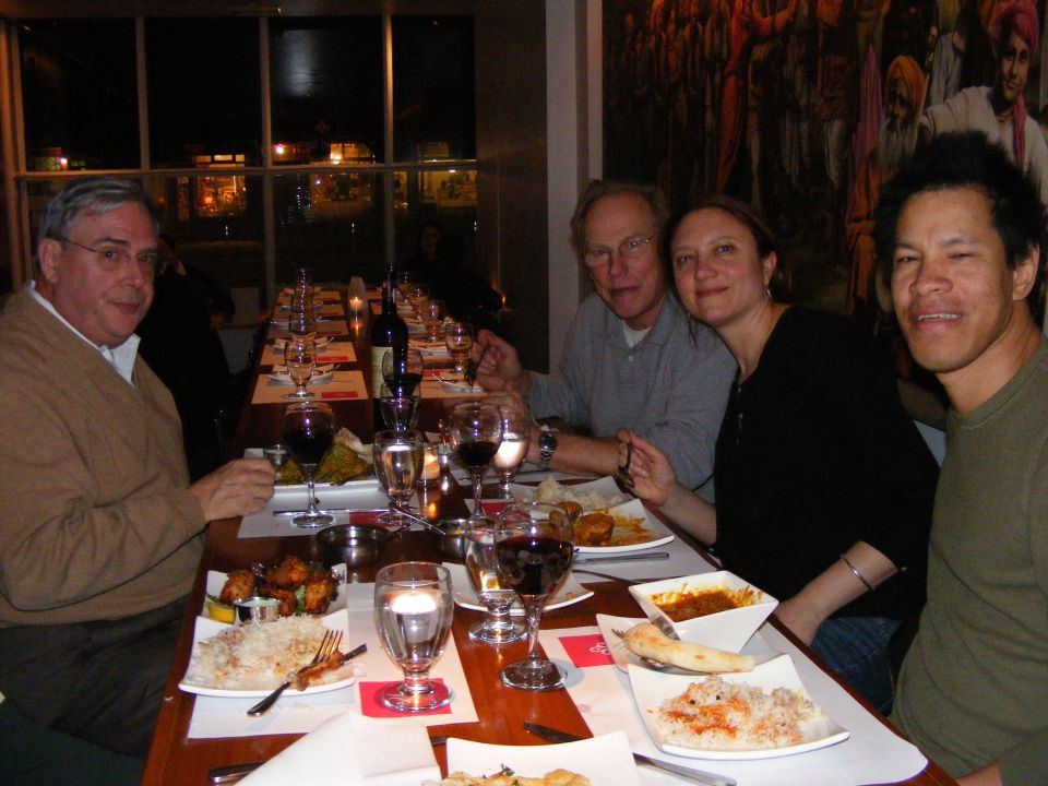 People dining at a restaurant table with food and wine.