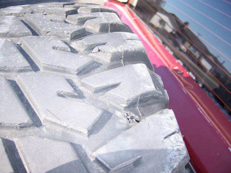 Close-up photo of a mud-terrain tire tread on a red vehicle