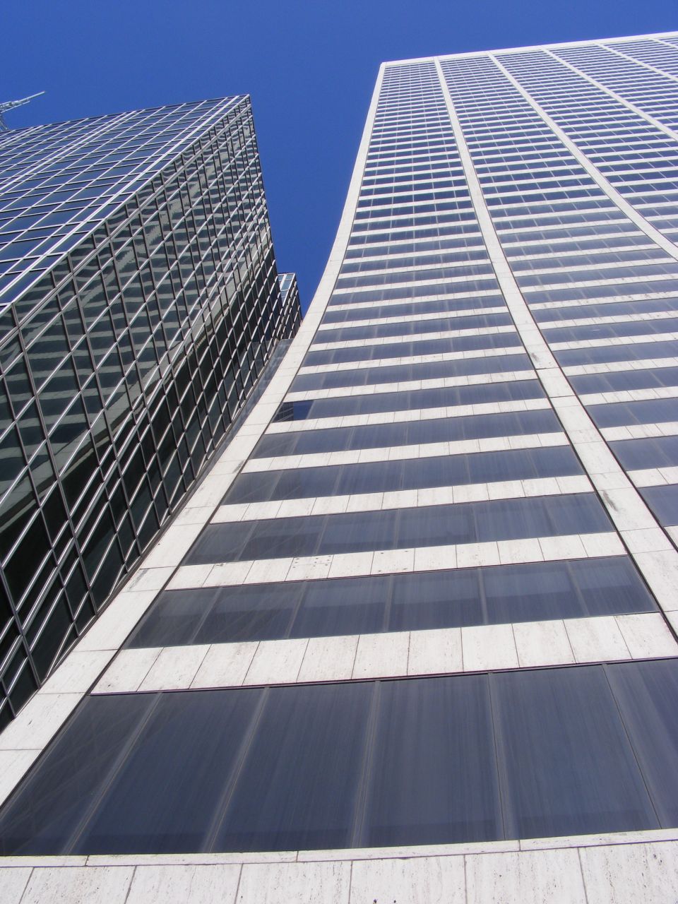 Two modern skyscrapers with glass facades against a clear blue sky.