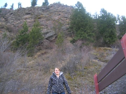 1996 Ford Bronco - A young woman stands in front of a rocky hillside with trees. She is wearing a dark hooded jacket with a white star pattern.
