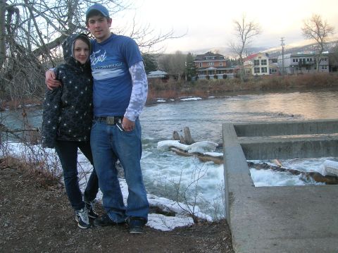 1996 Ford Bronco - A young couple poses for a photo by a river with snow and ice on the banks. Buildings and trees are visible in the background across the ri…