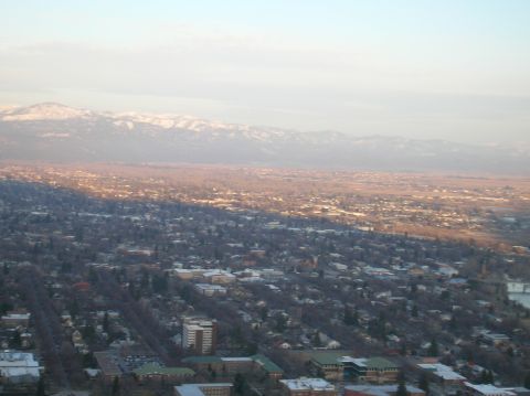 1996 Ford Bronco - An aerial view of a city with snow-capped mountains in the background under a hazy sky.