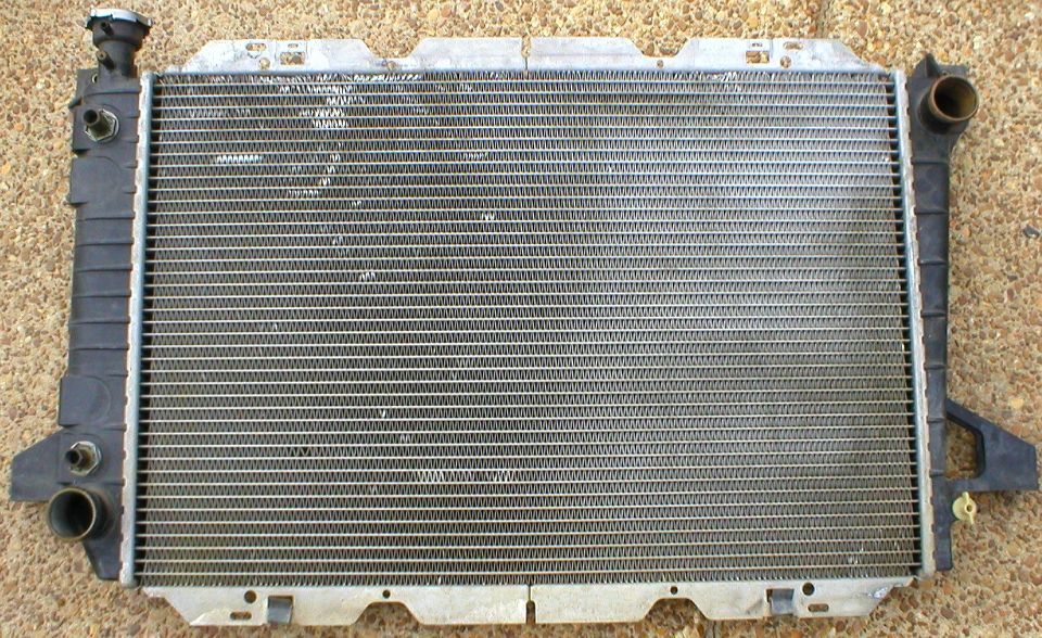 Radiator core laid face-up on cardboard, plastic end tanks and inlet/outlet necks visible