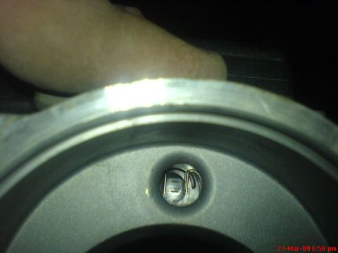 1992 Ford Crown Victoria - Close-up view inside a metal housing, possibly part of an engine or transmission, with a glimpse of a hand above. A small circular opening…