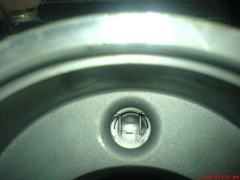 1992 Ford Crown Victoria - A close-up, low-angle shot looking into a metallic component with a small glass lens in the center. The lens reveals a metallic filament or…