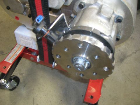 1996 Ford Bronco - A close-up view of a mechanical component, possibly part of a drivetrain, mounted on a red engine stand. A black and red strap is visible s…