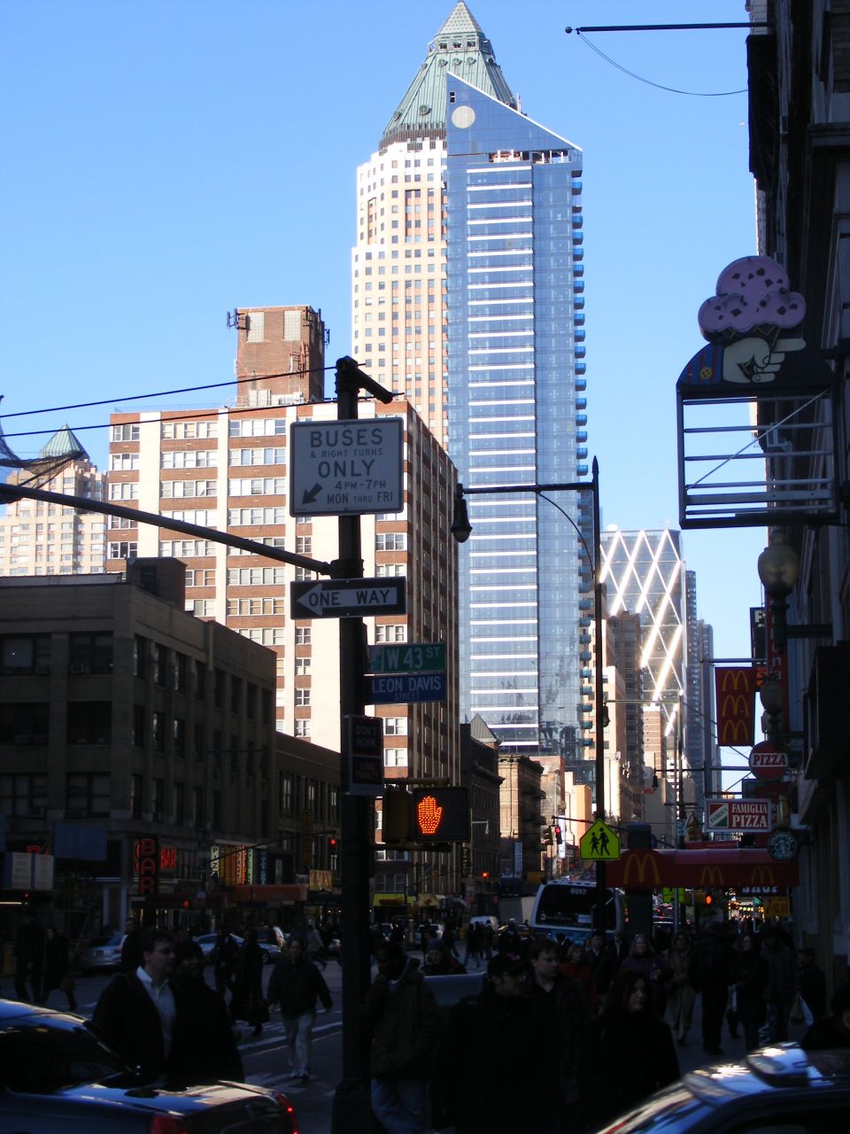 Street scene in New York City with buildings, signs, and pedestrians.