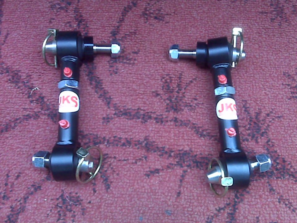 Two black adjustable control arms with JKS stickers.