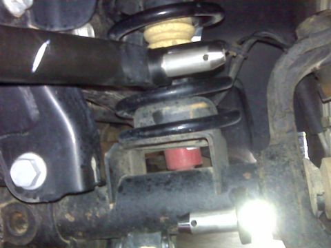 2008 Jeep Wrangler - A close-up view of the suspension components of a 2008 Jeep Wrangler, showing the coil spring, shock absorber mount, and control arm.
