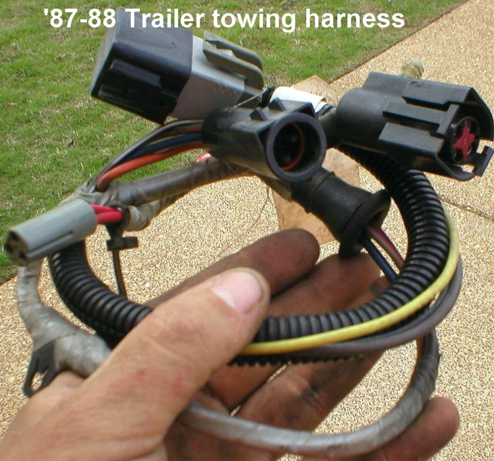 Hand holding a trailer towing wiring harness with multiple connectors, labeled '87-88