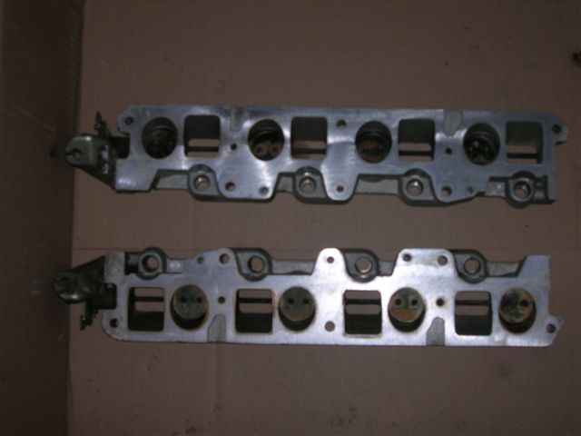 Pair of lower intake manifold or cylinder head castings on cardboard