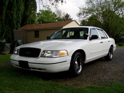 1999 Ford Crown Victoria - A white 1999 Ford Crown Victoria is parked in a driveway with a garage in the background.