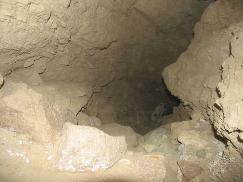 1984 Ford Bronco - A pair of white and black athletic shoes are visible lying on the ground inside a cave or tunnel.