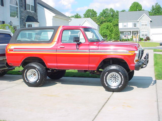 Red lifted vintage Ford Bronco SUV in a residential driveway