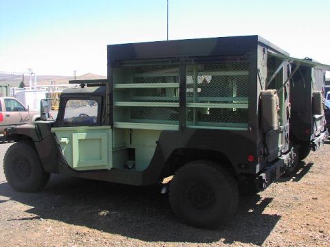 1981 Ford Bronco - Military truck modified with extensive shelving and storage compartments visible through open doors.