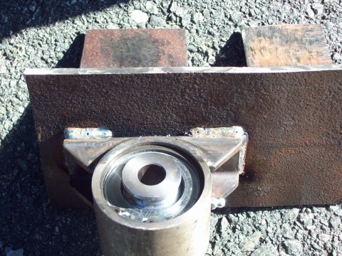 1989 Ford F-150 - A close-up view of a metal bracket with a bearing, welded together and placed on a gravel surface.