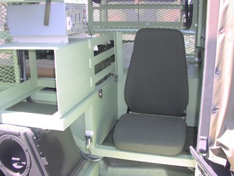 1981 Ford Bronco - The interior of a military vehicle features a single seat and various equipment mounted within the cabin.