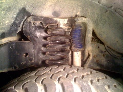 1996 Ford Bronco - Close-up of a vehicle's front suspension system, showing a coil spring and shock absorber.