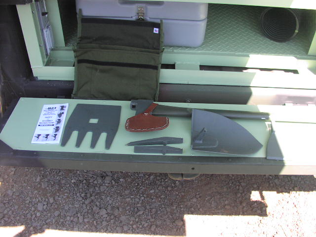 Green storage compartment with shovel, axe, and other tools laid out on a shelf
