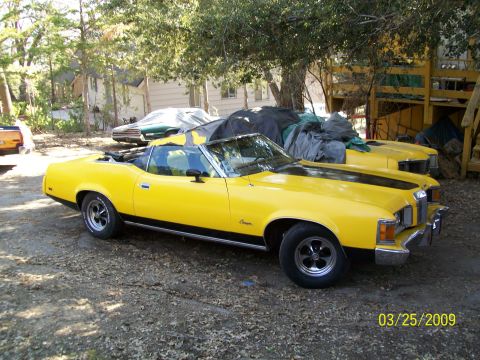 1973 Mercury Cougar - 1973 Mercury Cougar convertible in yellow, parked next to another car.