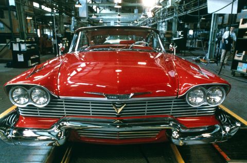 1985 Ford Bronco - A classic red automobile is seen from the front, likely in a manufacturing facility.