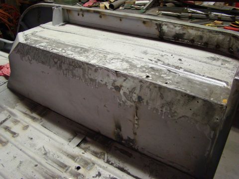 1948 Jeep Wrangler - A bare metal vehicle body panel is shown undergoing repair work, with tools and materials visible in the background.